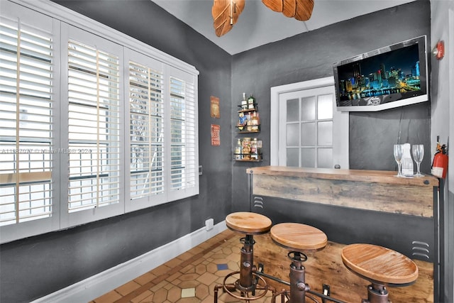 bar with a wealth of natural light, tile flooring, and ceiling fan