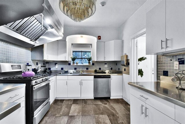 kitchen featuring tasteful backsplash, stainless steel counters, white cabinetry, wall chimney exhaust hood, and appliances with stainless steel finishes