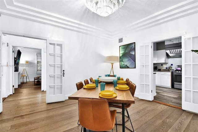 dining space with light wood-type flooring, french doors, and a chandelier