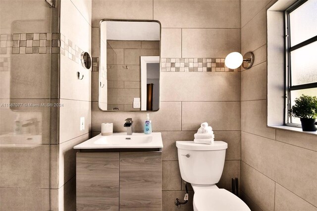 bathroom with tile walls, vanity, and toilet