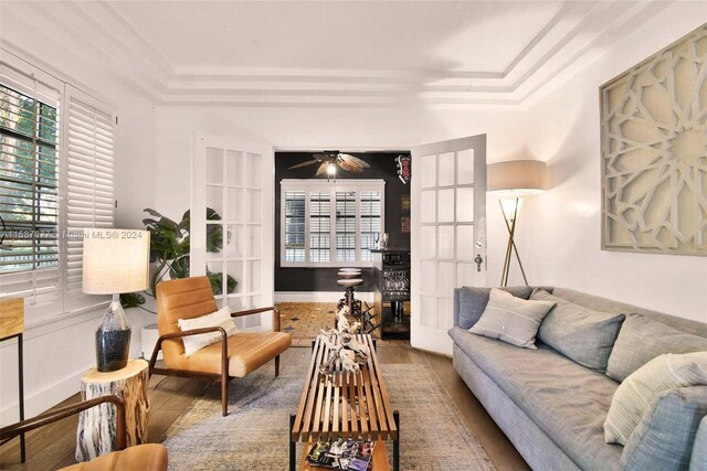 living room with ceiling fan, a tray ceiling, french doors, and wood-type flooring