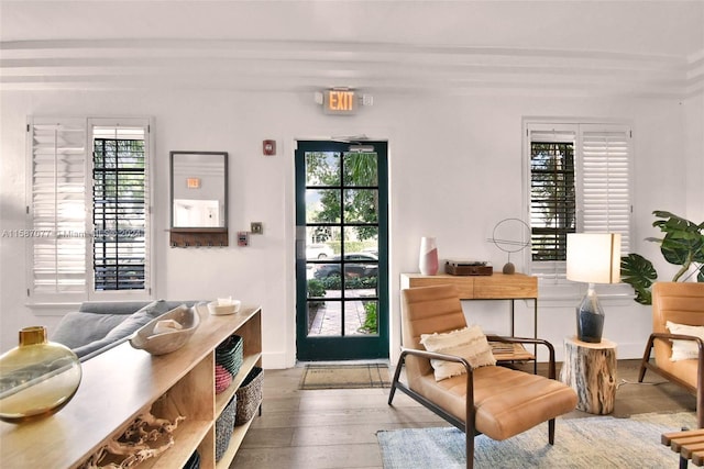 sitting room with a wealth of natural light, wood-type flooring, and beam ceiling