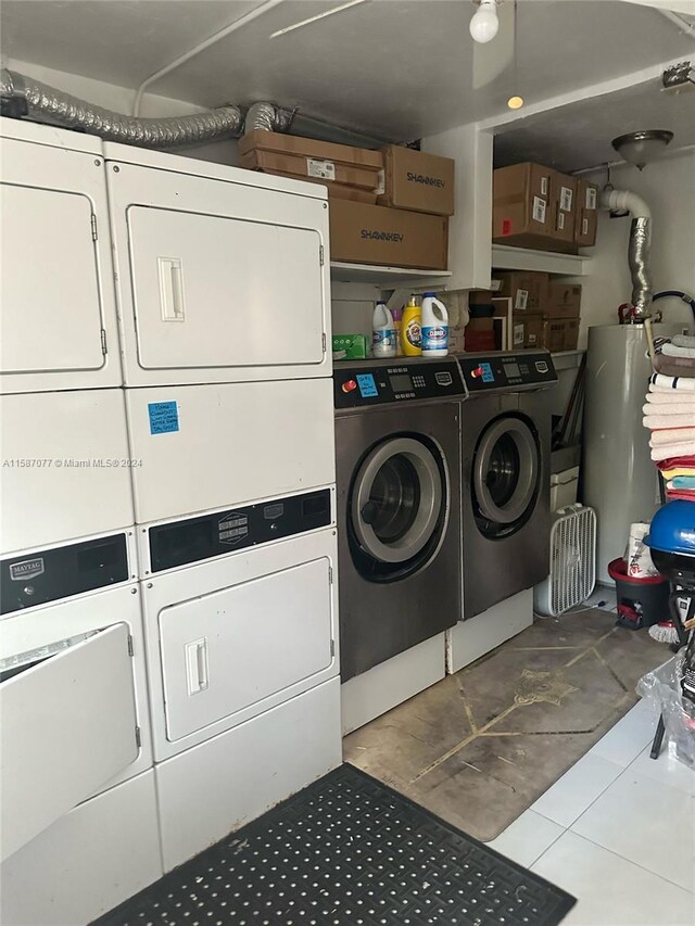 laundry room featuring stacked washer / dryer, light tile flooring, and water heater