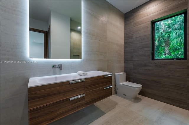 bathroom with vanity, toilet, and tile walls