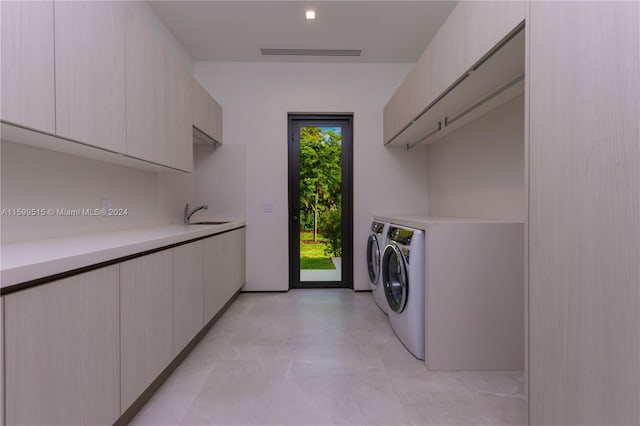 clothes washing area with cabinets, sink, and washing machine and clothes dryer