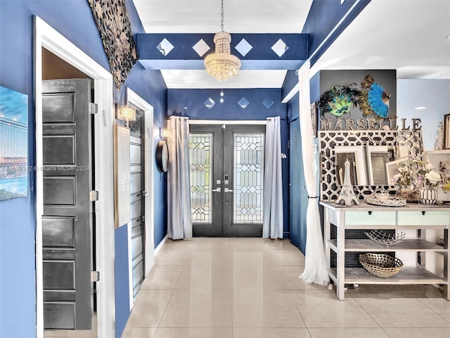 foyer entrance with a chandelier, light tile patterned floors, and french doors