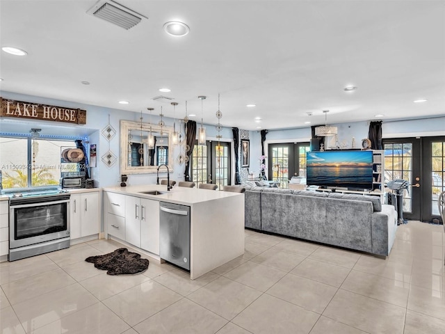 kitchen featuring sink, french doors, pendant lighting, light tile patterned floors, and appliances with stainless steel finishes