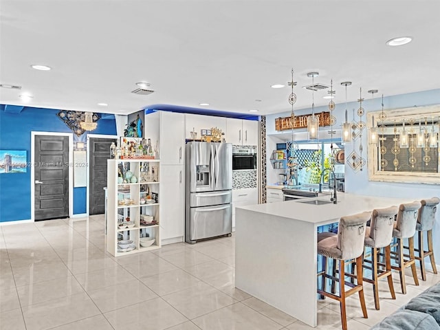 kitchen with kitchen peninsula, sink, decorative light fixtures, white cabinets, and stainless steel fridge with ice dispenser