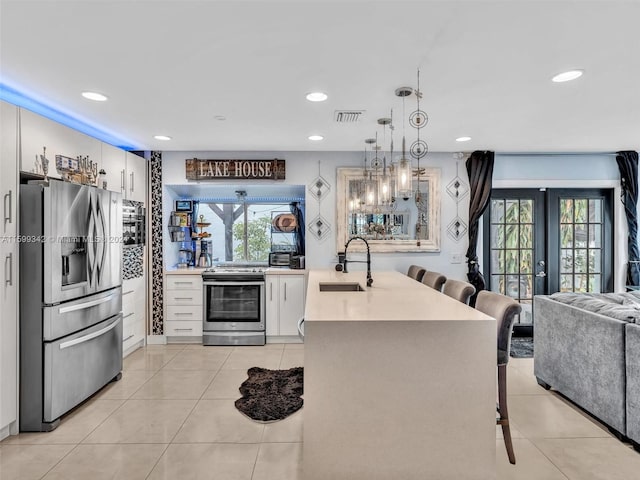 kitchen featuring stainless steel appliances, sink, white cabinets, hanging light fixtures, and a breakfast bar area