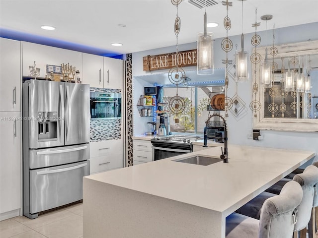 kitchen with white cabinets, appliances with stainless steel finishes, hanging light fixtures, and light tile patterned flooring