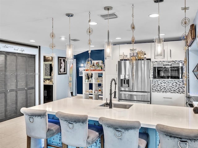 kitchen featuring oven, sink, decorative light fixtures, white cabinetry, and stainless steel fridge with ice dispenser