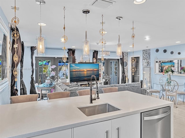 kitchen featuring french doors, sink, dishwasher, white cabinetry, and hanging light fixtures