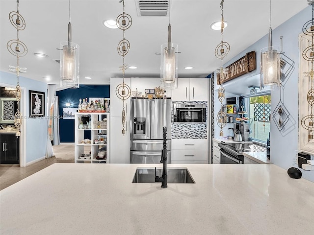 kitchen featuring white cabinets, appliances with stainless steel finishes, and hanging light fixtures