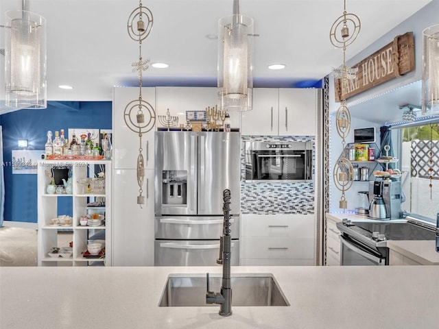 kitchen with pendant lighting, sink, white cabinetry, and stainless steel appliances