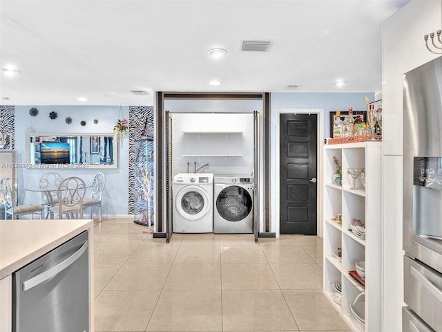 kitchen featuring independent washer and dryer, stainless steel appliances, and light tile patterned floors