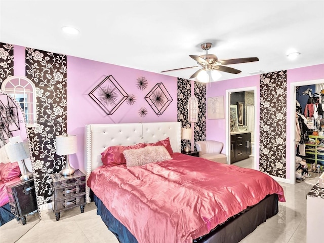 tiled bedroom featuring a walk in closet, connected bathroom, a closet, and ceiling fan