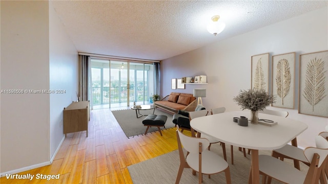 dining room featuring expansive windows, light wood-type flooring, and a textured ceiling