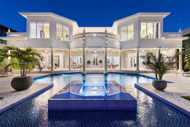 pool at twilight featuring an in ground hot tub and a patio