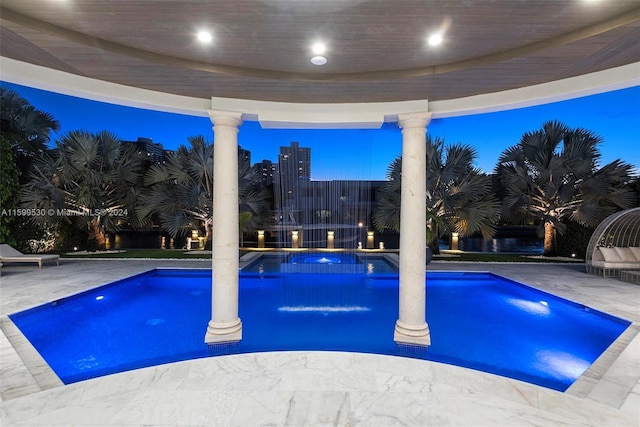 pool at dusk with an in ground hot tub and a patio area