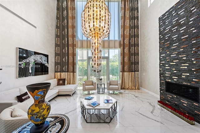 sitting room featuring a tiled fireplace, a towering ceiling, and a chandelier