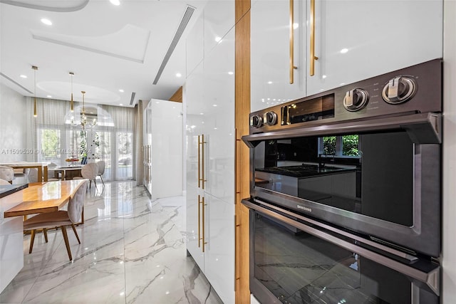 kitchen featuring pendant lighting, stainless steel double oven, and white cabinetry