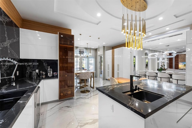 kitchen with a spacious island, dishwasher, dark stone countertops, and hanging light fixtures