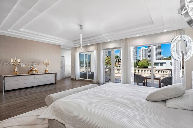 bedroom with access to outside, a tray ceiling, and dark hardwood / wood-style floors