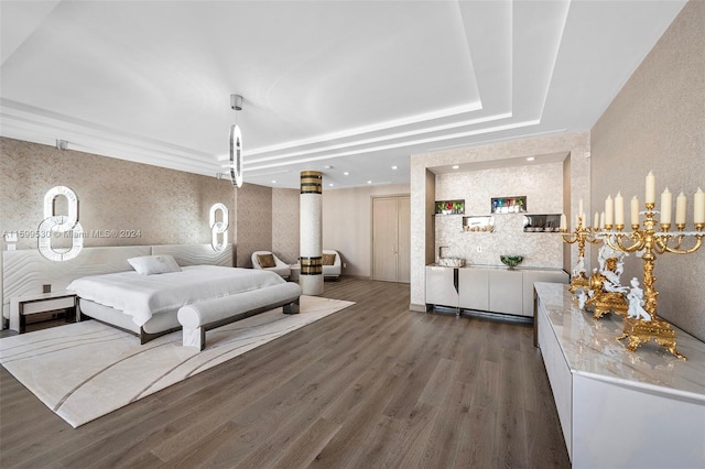 bedroom featuring a tray ceiling, dark hardwood / wood-style flooring, and an inviting chandelier