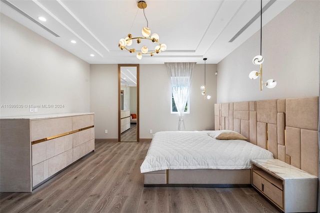 bedroom featuring a chandelier, hardwood / wood-style floors, and a tray ceiling