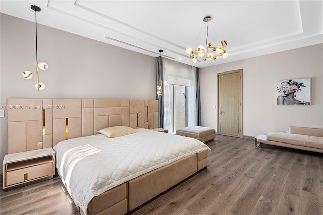 bedroom with a chandelier, hardwood / wood-style floors, and a raised ceiling