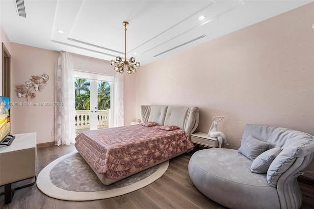 bedroom with access to outside, dark hardwood / wood-style floors, an inviting chandelier, and a tray ceiling