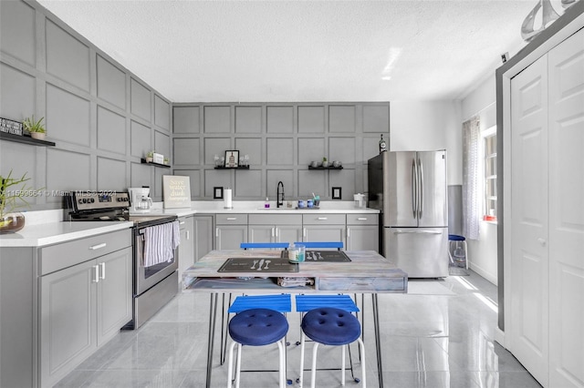 kitchen with gray cabinets, appliances with stainless steel finishes, a textured ceiling, and sink