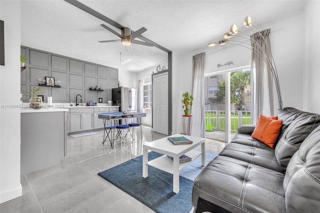 living room featuring a textured ceiling, sink, and ceiling fan