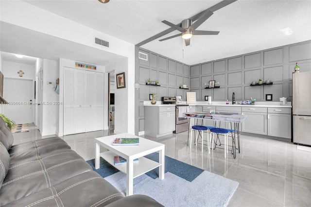 living room featuring a textured ceiling, sink, and ceiling fan