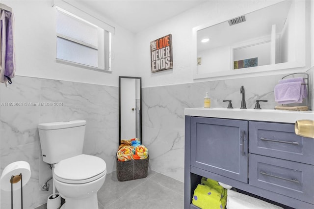 bathroom with vanity, toilet, tile walls, and tile patterned floors