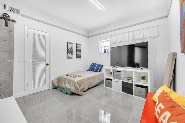 bedroom with a barn door, a closet, and light tile patterned floors