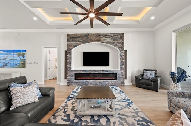 living room with ornamental molding, coffered ceiling, light hardwood / wood-style floors, and a stone fireplace