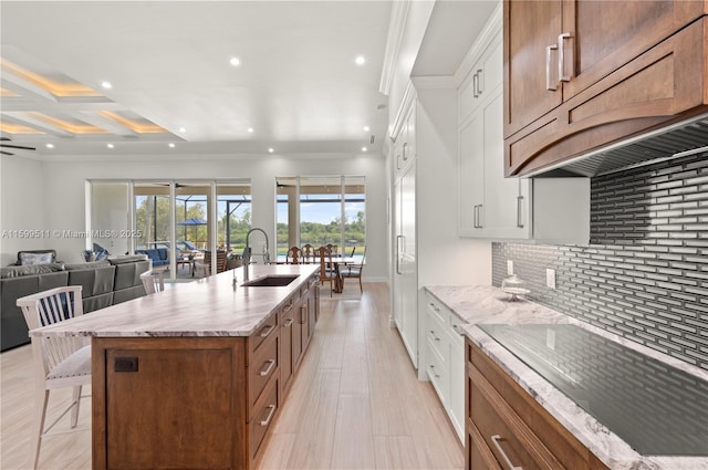 kitchen featuring a spacious island, a kitchen bar, sink, tasteful backsplash, and white cabinets