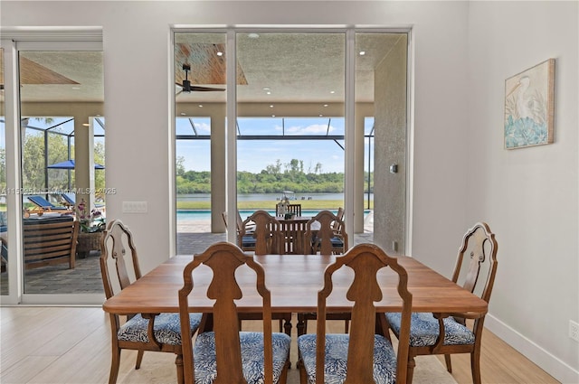 dining space featuring a water view, plenty of natural light, and light hardwood / wood-style flooring