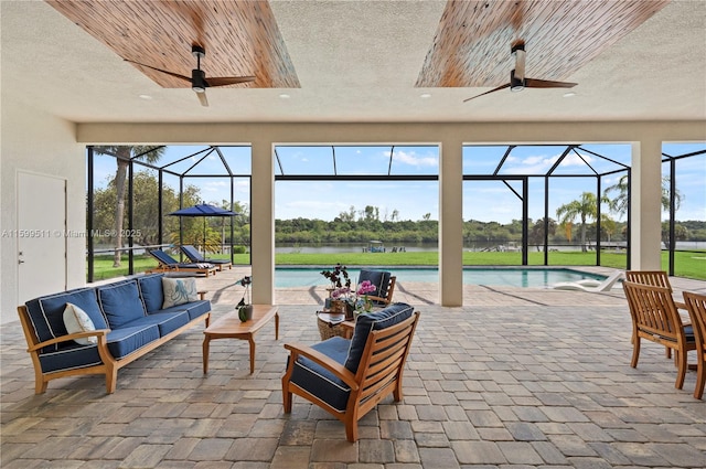 view of patio featuring a water view, ceiling fan, outdoor lounge area, and glass enclosure