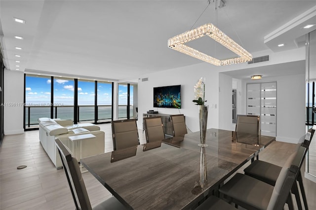 dining area featuring wood-type flooring, a water view, and expansive windows