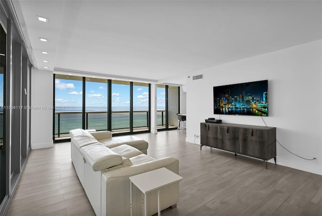 living room featuring floor to ceiling windows, a water view, and light hardwood / wood-style floors