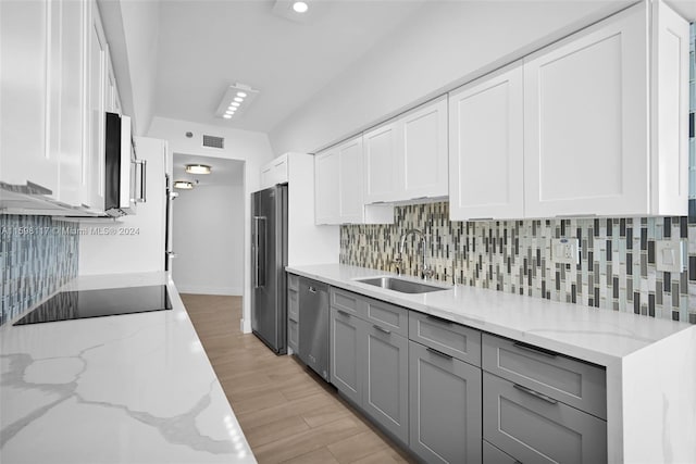 kitchen with stainless steel appliances, sink, backsplash, and light hardwood / wood-style flooring