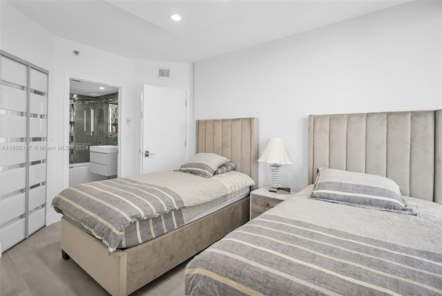 bedroom with light hardwood / wood-style floors and connected bathroom