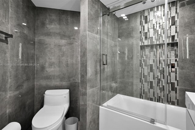 9455 Collins Ave Unit 809, Surfside, FL 33154 - full bath featuring bath / shower combo with glass door, toilet, and tile walls