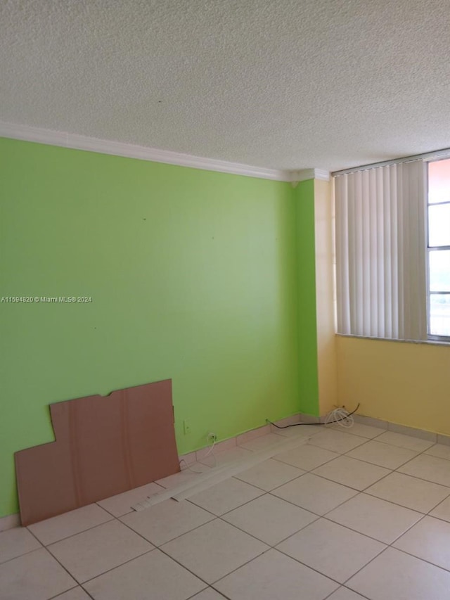 tiled spare room featuring ornamental molding and a textured ceiling