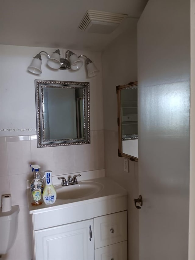 bathroom with vanity, tile walls, and toilet