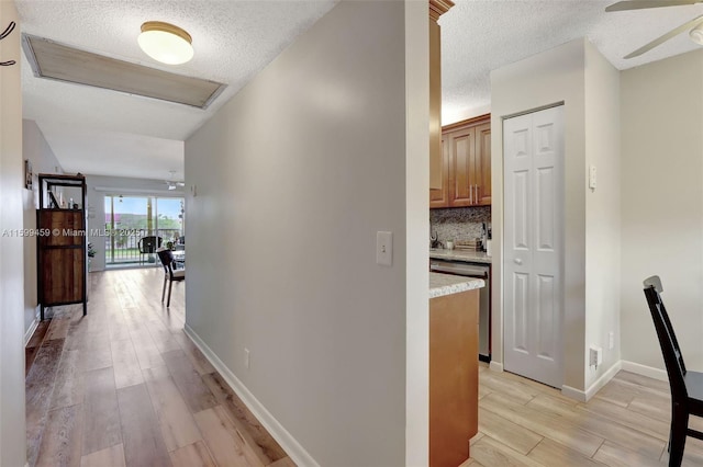 hall with a textured ceiling and light wood-type flooring