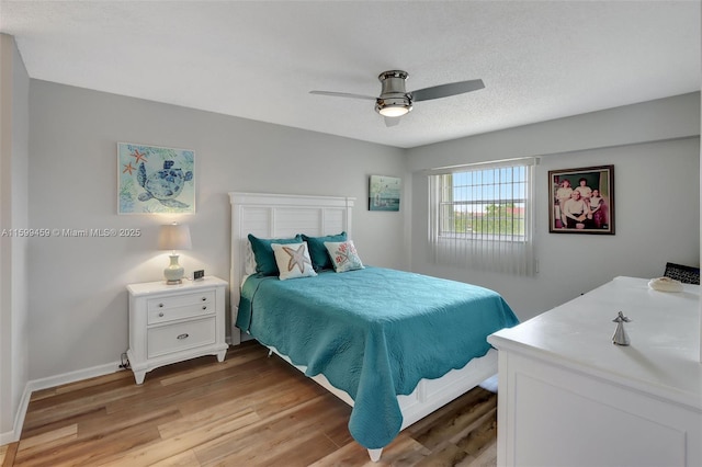 bedroom featuring ceiling fan, light hardwood / wood-style flooring, and a textured ceiling