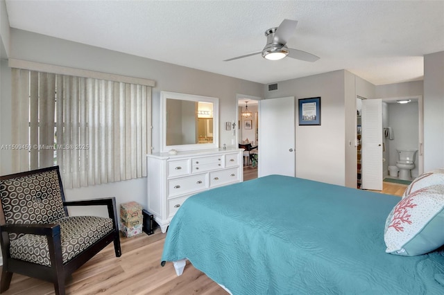 bedroom with ceiling fan, ensuite bathroom, light hardwood / wood-style floors, and a textured ceiling